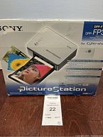 Boxed Sony PictureStation printer with product image and branding showing model DPP-FP30 and compatibility with Cyber-shot cameras.