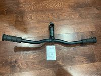 Full view of Specialized Steam handlebar with grips, showing the entire length on a wooden floor.