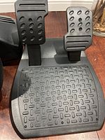 Close-up of pedal set with accelerator and brake pedals on textured base.