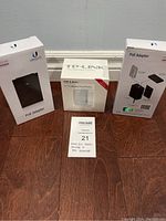 Front view of all three boxed items: one TP-LINK wireless travel router box flanked by two Ubiquiti POE adapter boxes.