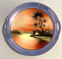 Top view of handpainted sunset design on Noritake plate with purple-blue border and cutout handles.