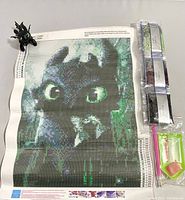 Full view of diamond painting canvas showing Toothless the Dragon's face with included items: two small figurines and diamond painting tools.