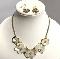 Gold toned flower necklace with five layered translucent flowers accented with rhinestones, displayed on neck form with matching pierced dangle earrings above.