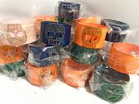 Photo showing multiple wrist cuff bracelets in original plastic wrap with rhinestone skull designs in varied colors stacked in a pile.