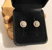Pair of round sterling silver post earrings with cluster center and beaded border, displayed in black jewelry box