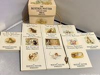 Photo showing the open chest filled with the 11 small Beatrix Potter collection Part 2 books laid out in two rows and the pin next to them