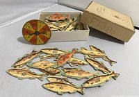 Photo showing the vintage cardboard spinner and fish-shaped game pieces inside and outside a labeled cardboard box