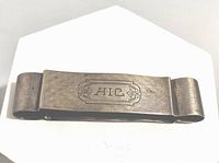 Front view of the vintage sterling silver notepad and pen holder band showing the monogram 'AIC' engraved in a decorative cartouche.