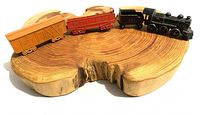 Three connected vintage painted metal model train cars on wooden surface, showing colors and sizes in natural light.