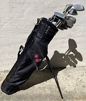 Full view of Jones Co. black golf bag with multiple golf clubs inside, standing upright with legs extended.