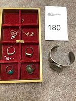 Overview on red velvet tray showing rings, necklace, loose stones and cuff bracelet on carpet