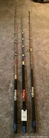 Three custom fishing rods laid on carpet floor showing full length and guide rings.