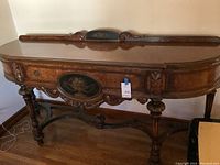 Front view of antique Berkey and Gay wooden ornate sideboard showing curved top, carved legs, floral painted oval panel, and stretcher base.