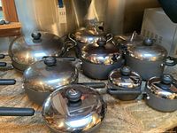 Full view of Circulon cookware set showing various pots and pans with glass lids and black handles on countertop.