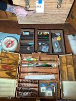 Photo showing open wooden fishing chest and tackle boxes arranged with fishing lures and accessories