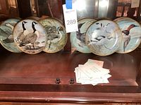 Overall view of the 9 Franklin Mint bird collector plates arranged side by side showing various bird illustrations and gold rims.