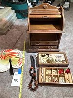 Full view of wooden jewelry box open with top and two bottom drawers removed, inset tray set in front along with fan and necklaces
