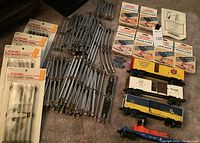 Overall image showing the collection of metal tracks, packaged track clips, and four train cars.