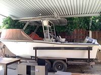 Side profile of white Mako 21 boat on trailer under carport