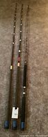 Full view of three fishing rods on carpet, different handle styles and lengths.