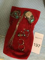 Overview on red pouch showing Timex watch with turquoise cuff band, silver‐tone turquoise cuff bracelet, multi‐strand necklace, two pairs of hoop earrings and one ring