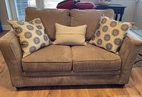 Front view of taupe loveseat with decorative pillows
