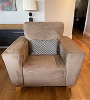 Front view of brown faux suede armchair with black and white geometric throw pillow revealing fabric and cushion details.