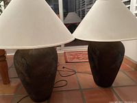 Pair of pottery lamps with dark brown textured bases and off-white shades, photographed indoors.