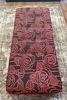 Top view showing rectangular shape, red rose floral pattern upholstery, and button tufting details.