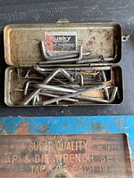 Metal case containing rusty Allen keys laid out inside, showing wear and usage on keys and case.