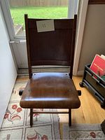 Front view of antique wooden folding chair showing seat and backrest.