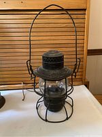 Front view showing wire cage, glass globe, ventilated top and bail handle