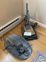 Photo showing antique scale with metal bowl weighing platform and dial, and bottle capper mounted on wooden base, positioned on hardwood floor corner