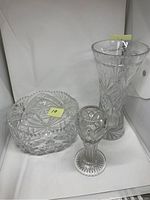 Photo showing the large cut crystal bowl, the small etched crystal vase, and the base of the tall crystal vase, all clear crystal with detailed cut patterns.