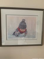 Full view of framed print showing child in winter clothing looking at snow, title and artist signature visible.