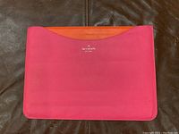 Front side of pink Kate Spade laptop/iPad case showing orange interior pocket and logo