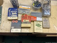 All items displayed on a workbench showing boxed nails, staples, plastic containers with assorted bolts, nuts, and screws