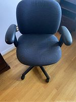 Front angle view of a gray office chair with curved armrests and cushioned seat and backrest.