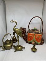 Full group shot showing ceramic camel tea pot, brass crane on turtle, brass kettle, bell, and incense burner.