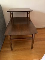 Photo showing one solid wood two-tier end table with a dark stain finish and rectangular top.