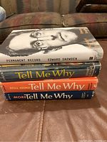 Side view of the four books stacked showing titles and condition.