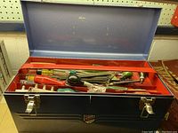 Photo of open blue metal tool box with red interior tray filled with various hand tools including screwdrivers and pliers