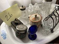 Assortment of salt and pepper shakers and related items on a tray showing various glass and metal designs with a ceramic covered container