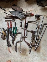 Various hand tools spread on floor including hand drills, tin snips, wrenches and files.