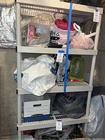 5 tier plastic shelf loaded with plastic bags and storage boxes in basement setting