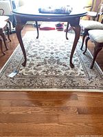 View of the area rug under a wooden table showing the full rug size and color scheme.