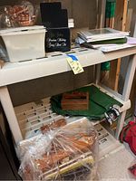 Photo of shelves with various art supplies, including stacks of paper, green fabric, wooden box, and other items in a basement setting.