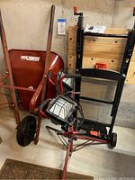 Shows Truetemper wheelbarrow, Black & Decker Workmate, and Craftsman work lights on stand grouped together against concrete wall.
