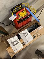 Porter & Cable brad nailer and finish nailer manuals visible on cardboard box with Husky red air compressor and yellow coiled hose behind.