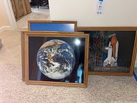 Two framed photos leaning, one with Earth and one with Space Shuttle Challenger.